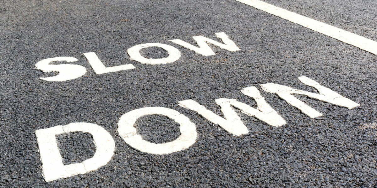Asphalt road with white text saying Slow Down.