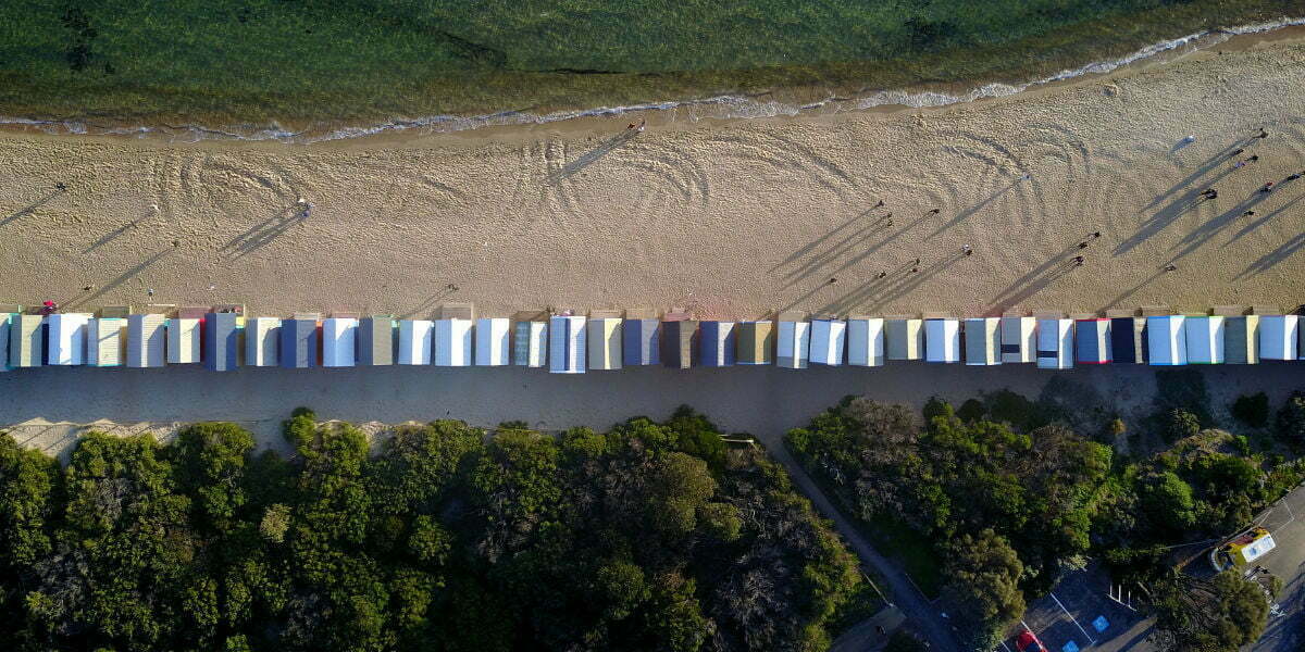 An aerial view of a beach and a long line of beach huts .
