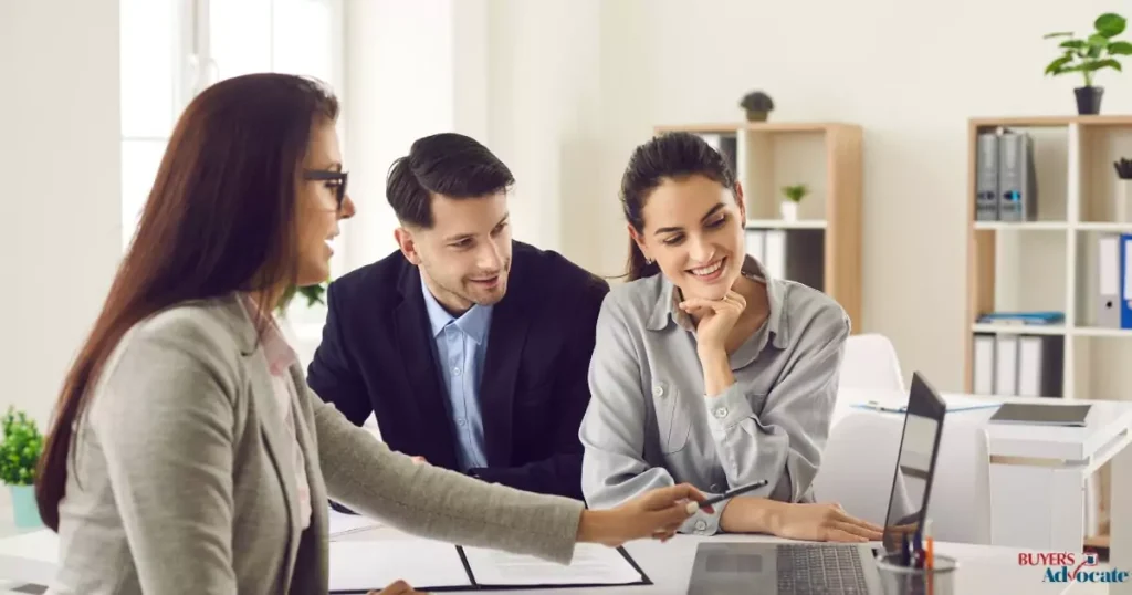 A property manager showing details on a laptop while discussing fees with a couple in Melbourne.